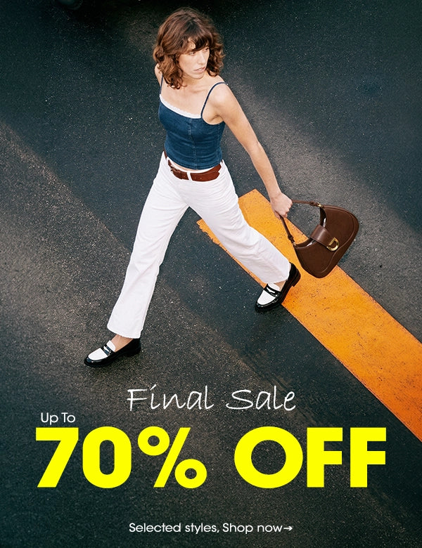 A woman walking across an orange road marking on dark asphalt, wearing a blue tank top, white pants, black shoes, and carrying a brown handbag. Large promotional text at the bottom reads 'Up To Final Sale 70% OFF'.